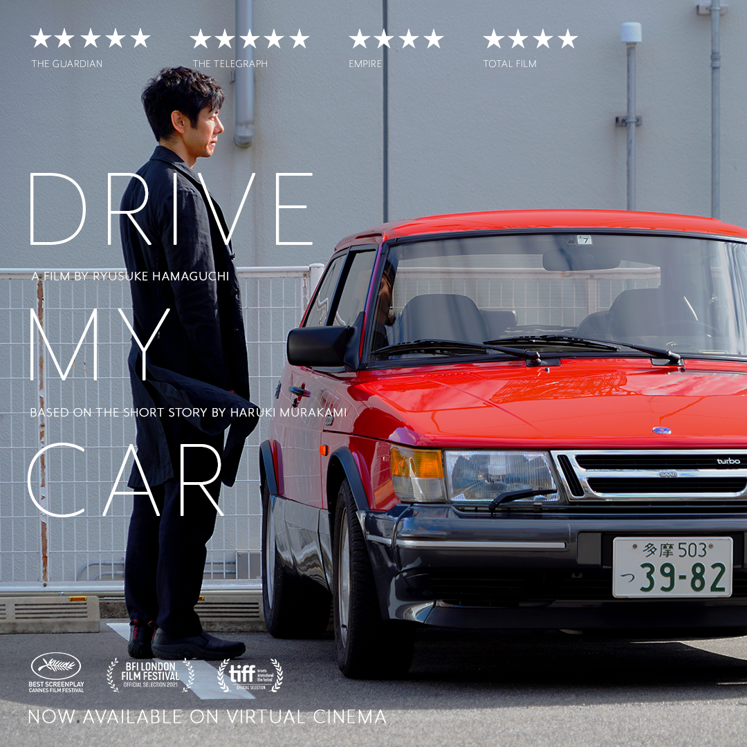 Man standing by red car with words 'Drive My Car'